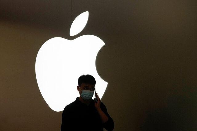 A man talks on a phone in front of an Apple logo outside its store in Shanghai